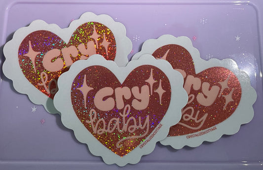 Heart shaped sparkly sticker with doily edge says cry baby