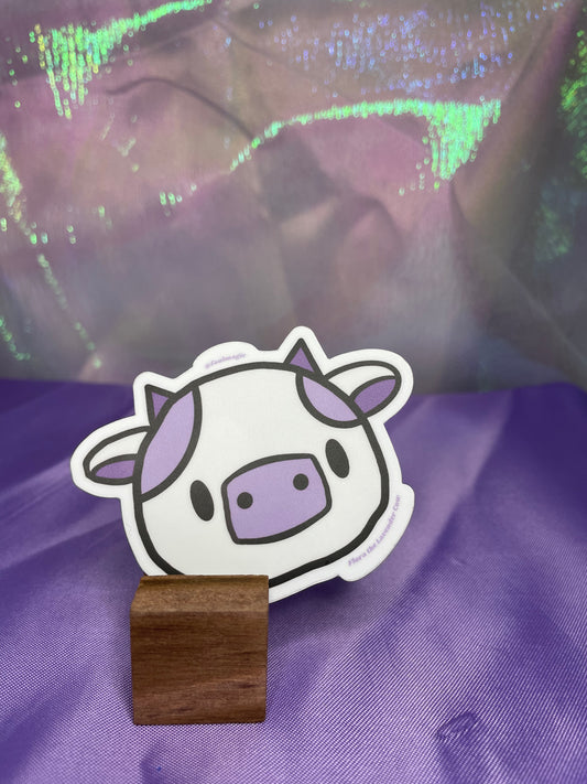Picture of a lavender and white colored cartoon cow sticker. The font underneath reads Flora the Lavender Cow